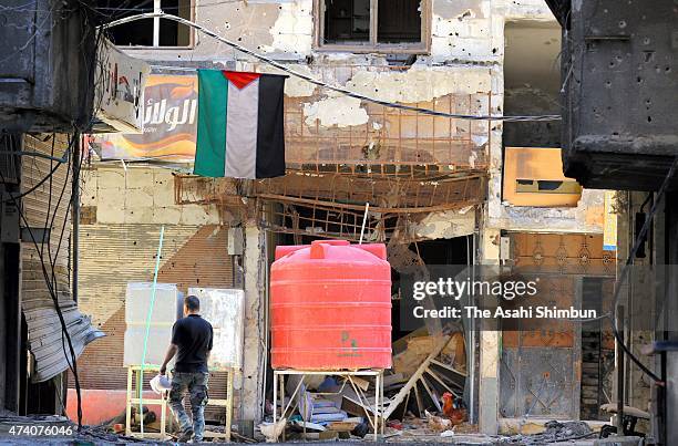 Man walks under the Palestine flag among debris at the government-occupied area, damaged by battles against the Islamic State militant group in the...