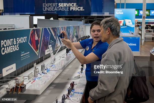 Customer gets help from an employee as he browses cameras on display in this photograph taken with a tilt-shift lens at a Best Buy Co. Store in San...