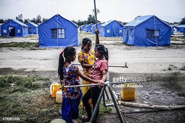 Nepalese girls wait to fill their buckets with fresh water at the earthquake survivors temporarily shelter in Kathmandu, Nepal on May 20 following...