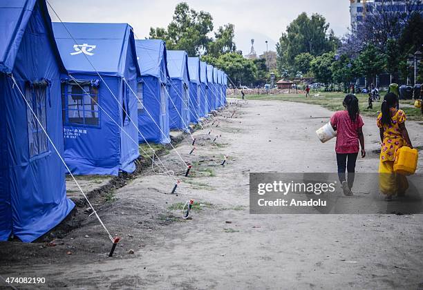 Nepalese girls walk with empty buckets to fill them with fresh water at the earthquake survivors temporarily shelter in Kathmandu, Nepal on May 20...