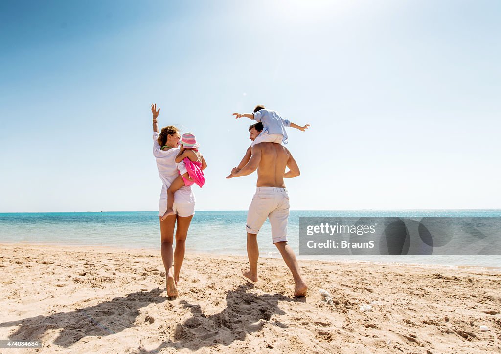Young happy parents having fun with their children at beach.