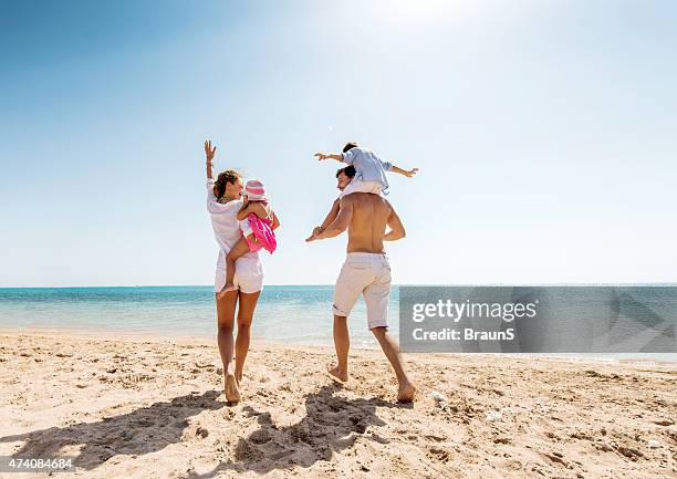 young happy parents having fun with their children at beach. - couple running on beach stock pictures, royalty-free photos & images