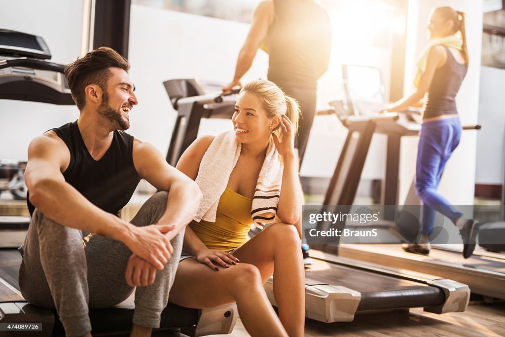 Young cheerful people resting from exercising at gym and communicating.