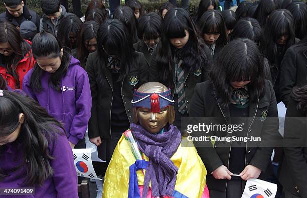 South Korean students pay a silent tribute beside a comfort woman statue during an anti-Japan rally in front of the Japanese embassy on February 22,...