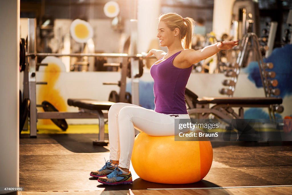 Woman doing balance exercises on a fitness ball at gym.