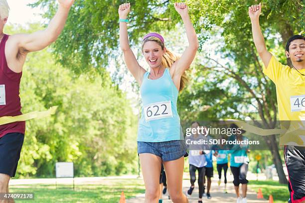 frau feiert gewinnen marathon oder 5 km lauf - marathon ziel stock-fotos und bilder