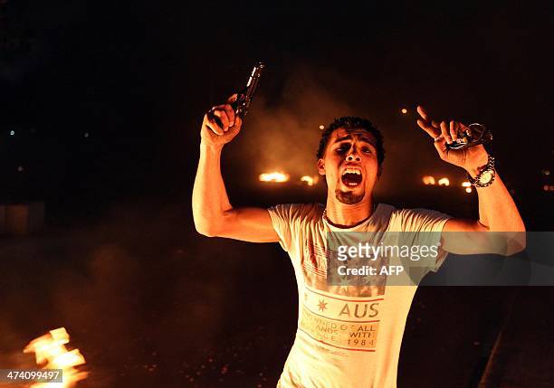 An armed Libyan demonstrator shouts slogans as they burn tyres blocking a main street in the eastern Libyan coastal city of Benghazi during a protest...