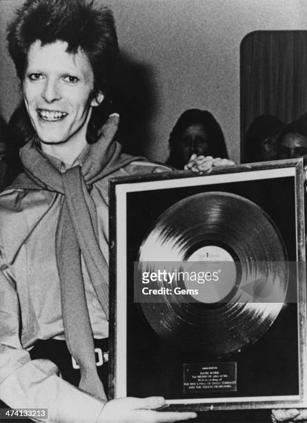 English rock singer-songwriter David Bowie with a gold record awarded to him for 100, 000 sales of his album, 'The Rise and Fall of Ziggy Stardust...