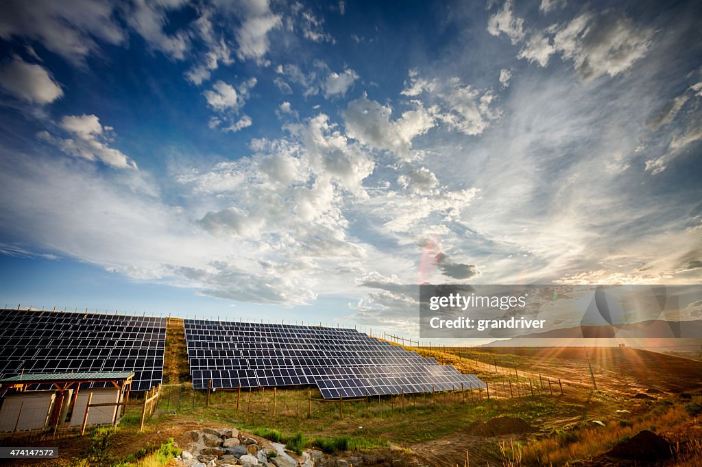 Panneaux solaires et champ vert sous le spectaculaire ciel au coucher du soleil