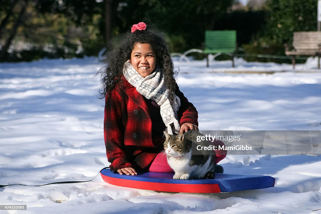 Cat and girl are sitting on top of the snow