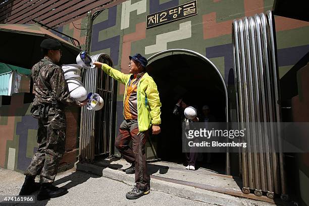 Visitor hands a helmet to a guard as he exits the Second Tunnel, an "infiltration" tunnel dug by North Korea, near the demilitarized zone in...