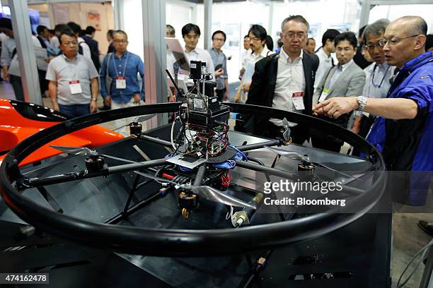 Multi-rotor unmanned aerial vehicle , developed by Autonomous Control Systems Laboratory Ltd., sits on display as a booth attendant, right, talks to...