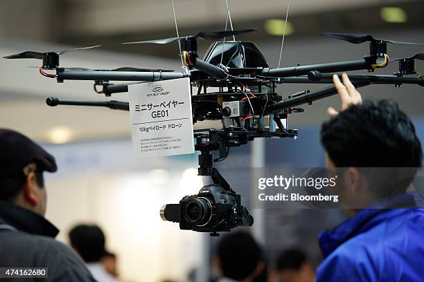 Canon Inc. EOS 5D Mark III digital single lens reflex camera hangs below a Mini Surveyor GEO 1 multi-rotor unmanned aerial vehicle , developed by...