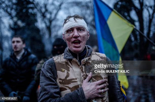 An anti-government activist places his hand over his heart after the vote of the Ukrainian Parliament as demonstrators rally outside the parliament...