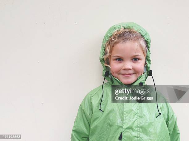 portrait of happy child wearing green rain coat - rain coat stock pictures, royalty-free photos & images