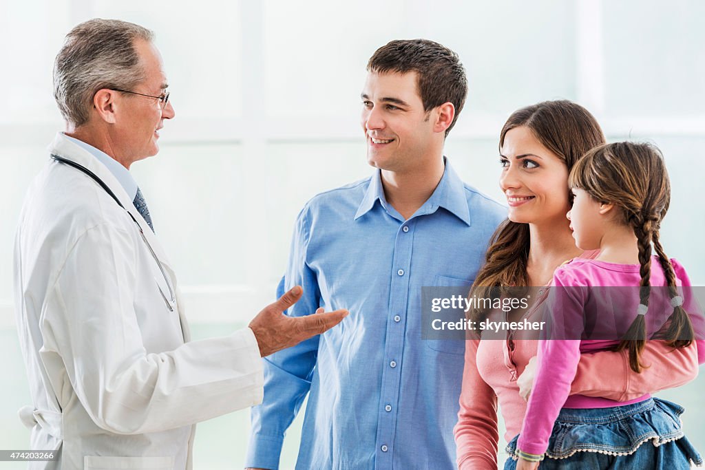 Young smiling family communicating with a mature doctor.