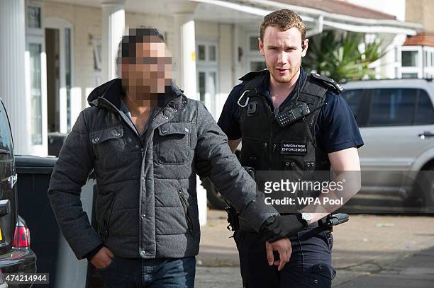 Sri Lankan man is led away by Immigration Enforcement officers after a raid on a residential property looking for illegal immigrants in Southall, on...