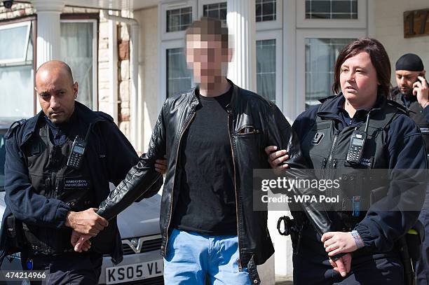 Romanian man is led away by Immigration Enforcement officers after a raid on a residential property looking for illegal immigrants in Southall, on...