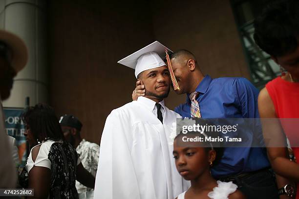 McDonogh Senior High School graduate Malik Hayes is hugged by his father Marlon at his commencement along with relative Tre'shyna at the Ernest N....