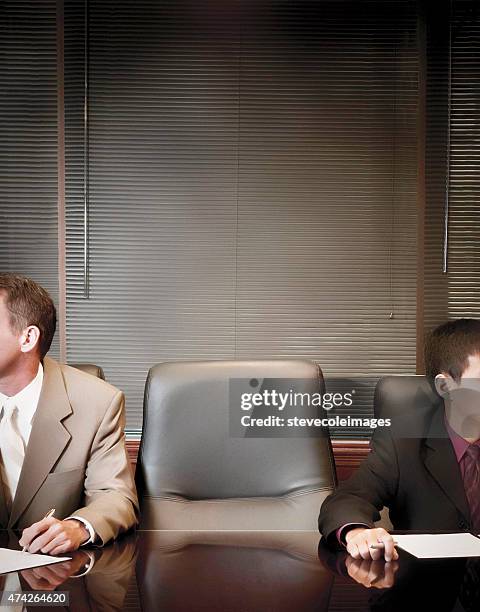 businessmen in boardroom with empty chair. - absentie stockfoto's en -beelden