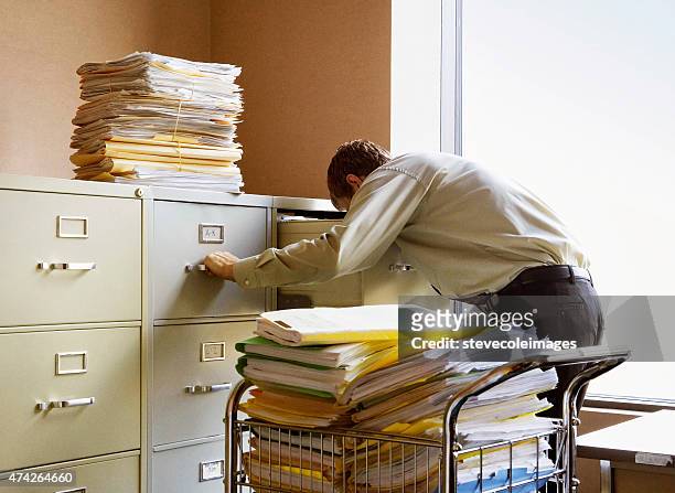 businessman searching for documents in metal file cabinets. - filing documents stock pictures, royalty-free photos & images