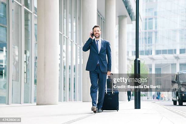 businessman on his cell phone with suitcase - bringing home the bacon engelse uitdrukking stockfoto's en -beelden