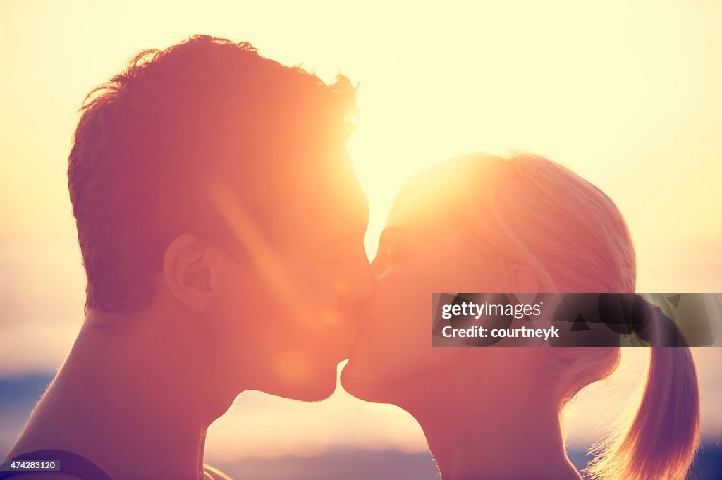 Young couple kissing each other at sunset.