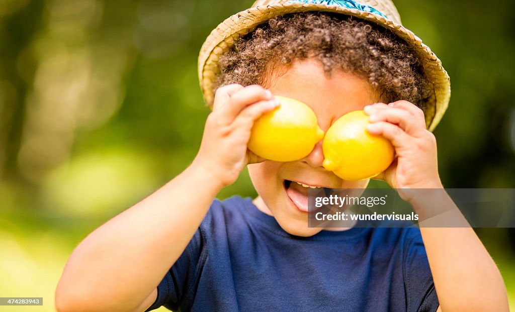 Boy in park holding lemons as eyes