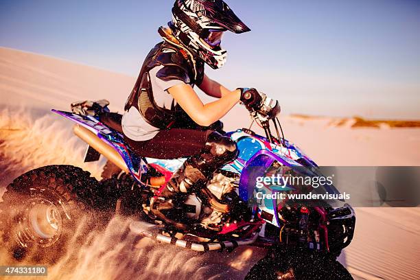 girl quad racer in protective gear racing over sand dunes - women motorsport stock pictures, royalty-free photos & images