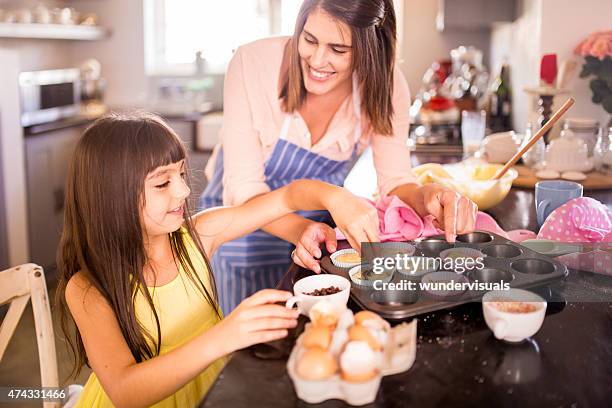 girl decorating cupcakes she is helping her mom make - decorating a cake stock pictures, royalty-free photos & images