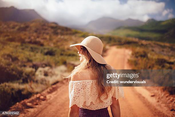 rearview of boho girl standing on dirt road in summer - beige hat stock pictures, royalty-free photos & images