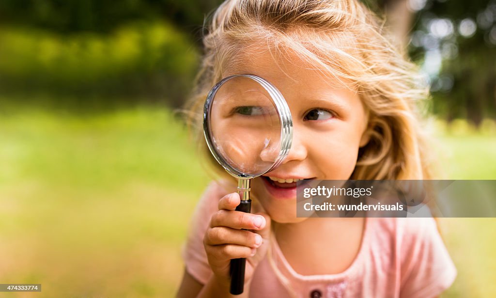 Exploring girl with magnifying glass in nature