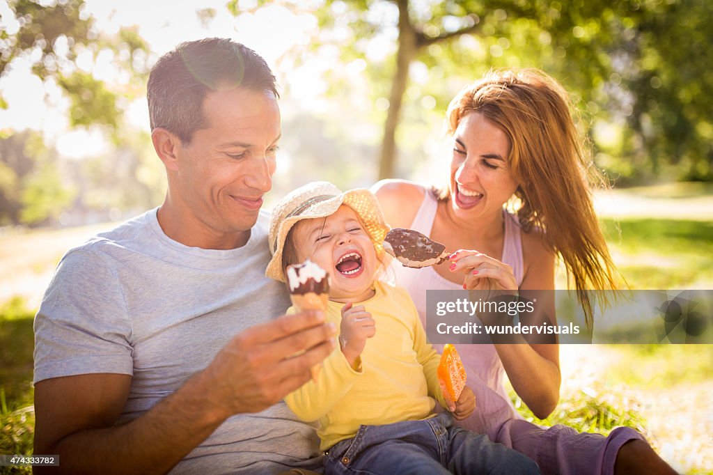 Young family happily eating ice creams together in a park