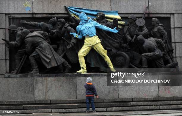 Boy looks at a figure painted in the colours of Ukraine on the monument of the Soviet Army in central Sofia on February 23, 2014. The main Soviet...