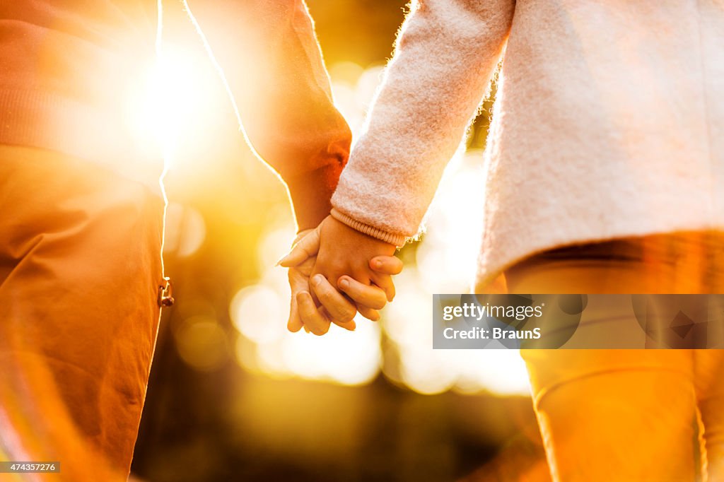 Rückansicht der gemachten Paar Hand in Hand bei Sonnenuntergang.