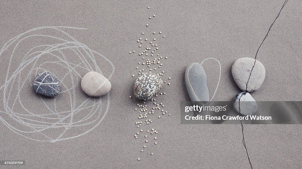 Pebbles on grey paper with chalk and ink lines