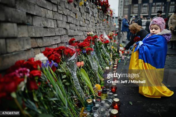 Young girl lays flowers left for anti-government demonstrators killed in clashes with police on February 22, 2014 in Kiev, Ukraine.Prime Minister...