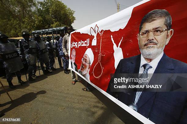 Police stand guard as Sudanese Islamists hold a poster bearing portraits of Egypt's ousted president Mohamed Morsi , Egyptian Muslim Brotherhood...