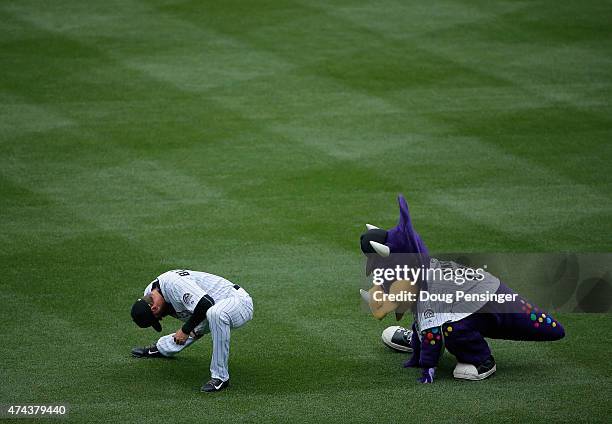 Charlie Blackmon of the Colorado Rockies is shadowed by Dinger the mascot as he stretches prior to facing the Philadelphia Phillies at Coors Field on...