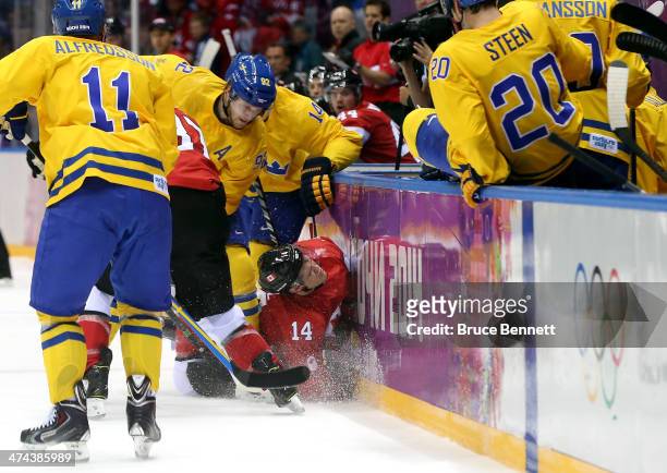 Chris Kunitz of Canada crashes into the boards against Gabriel Landeskog and Patrik Berglund of Sweden during the Men's Ice Hockey Gold Medal match...