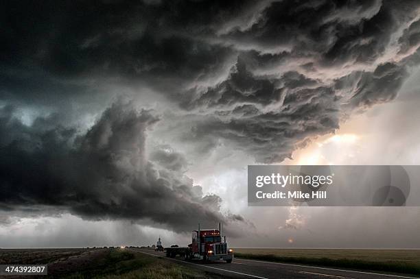 truck on road with gathering storm clouds - sturmbewölkung stock-fotos und bilder