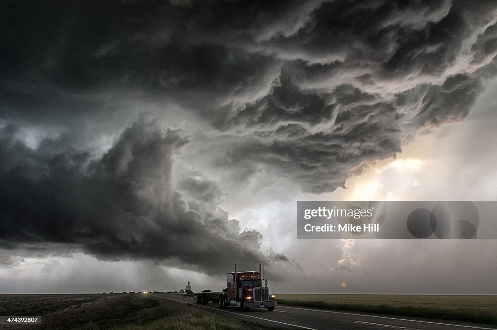 Truck on road with gathering storm clouds
