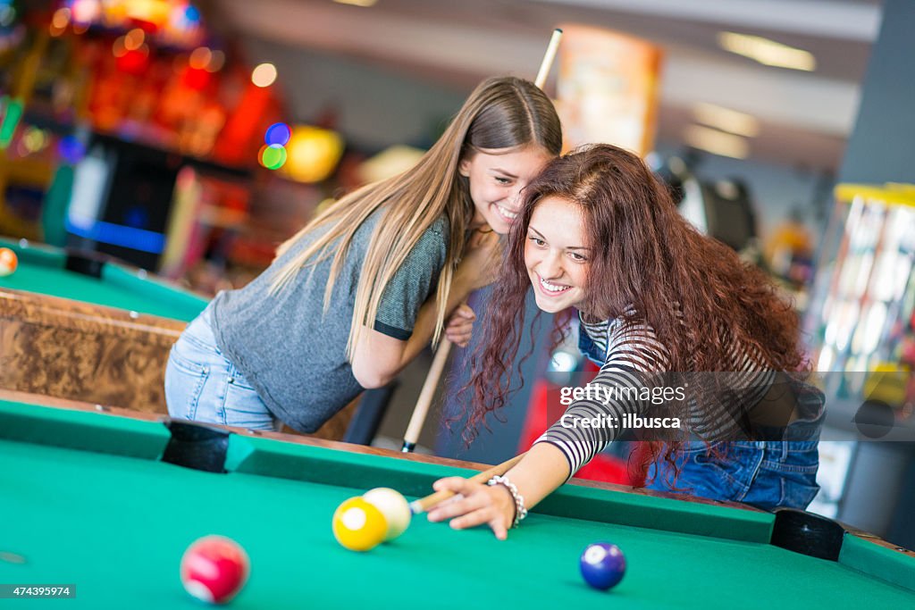 Two girls friends playing pool