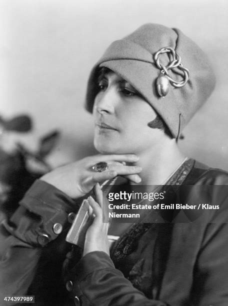 Young woman modelling a cloche hat with a decoration featuring an acorn design, circa 1925.