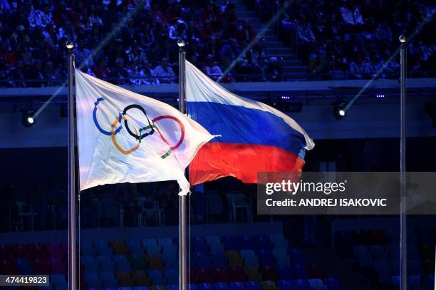Picture taken on February 23, 2014 shows the Olympic flag and the Russian flag flying during the Closing Ceremony of the Sochi Winter Olympics at the...
