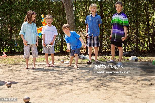 little girl playing ball game outdoors with boys suburb backyard. - petanque stock pictures, royalty-free photos & images