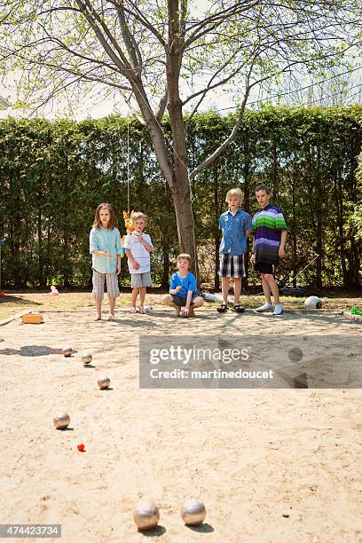 little girl playing ball game outdoors with boys suburb backyard. - petanque stock pictures, royalty-free photos & images