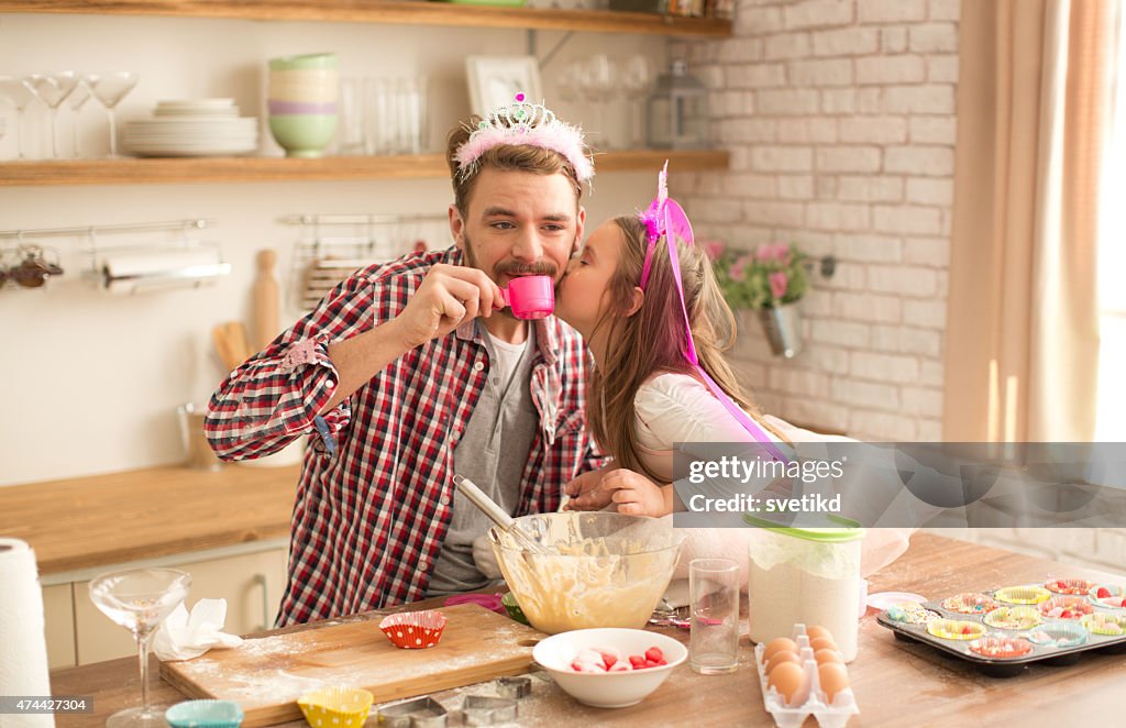 Father and daughter baking and having tea party in kitchen.