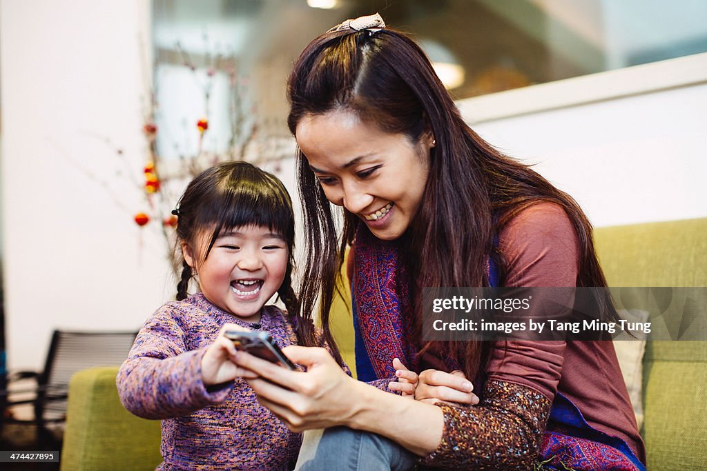 Mom & toddler looking at smartphone joyfully