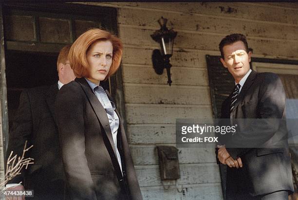 Agent Dana Scully and Agent John Doggett at the scene of a gruesome murder linked to a bat-like creature in the "Patience" episode of THE X-FILES...